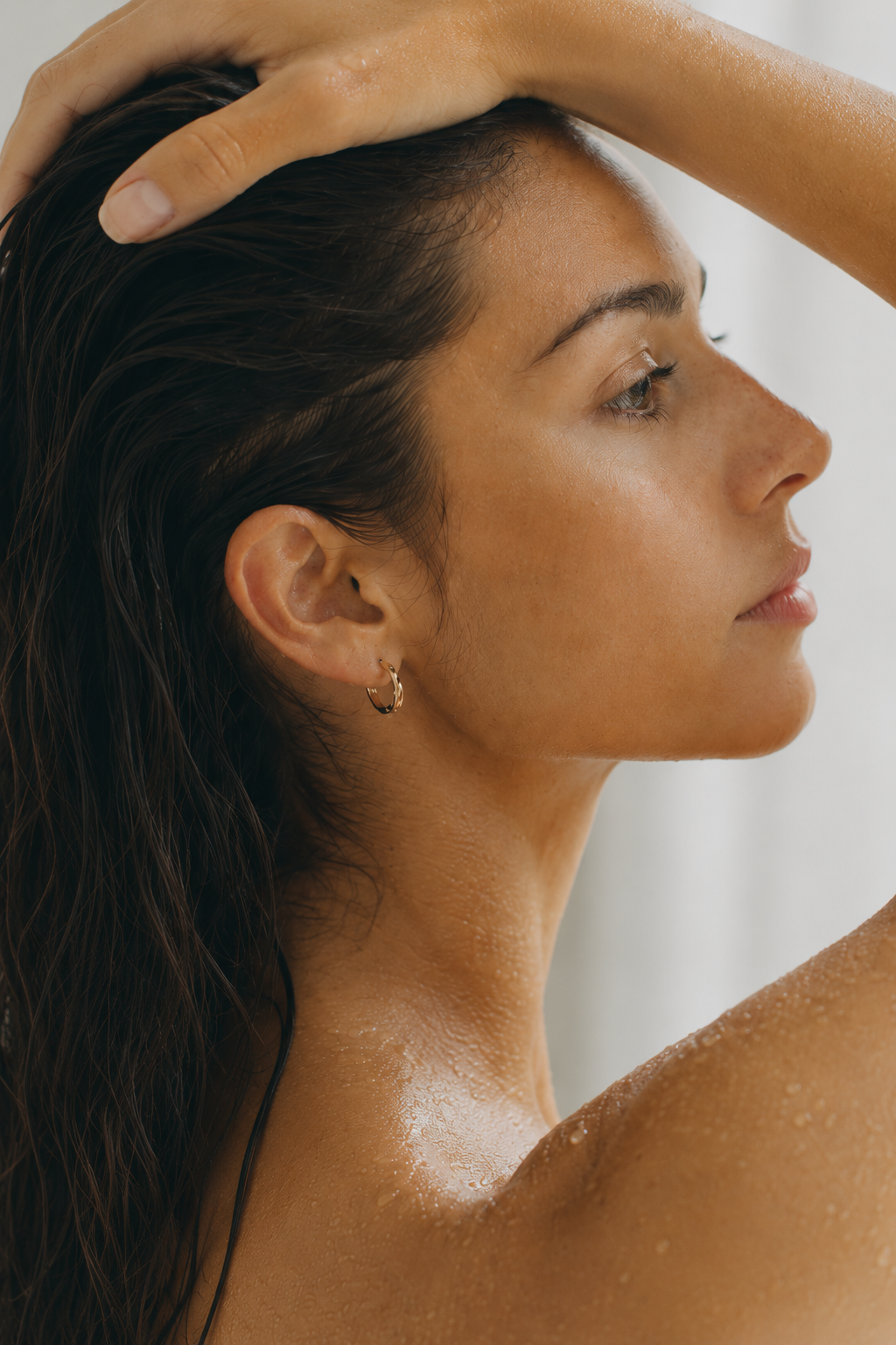 Woman in profile after a soft-water shower — smooth wet hair, calm skin